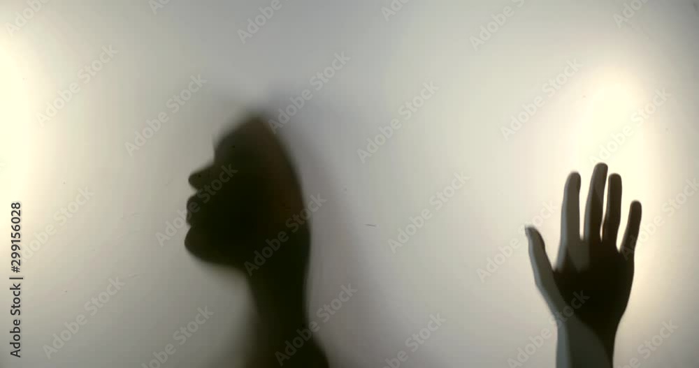 dark silhouette of female face and body behind white cloth, she is moving hands