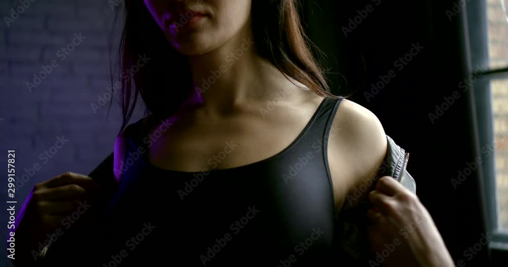 seductive young woman is putting off her black leather jacket from shoulders, slow motion seductive young woman is putting off her black leather jacket from shoulders, slow motion