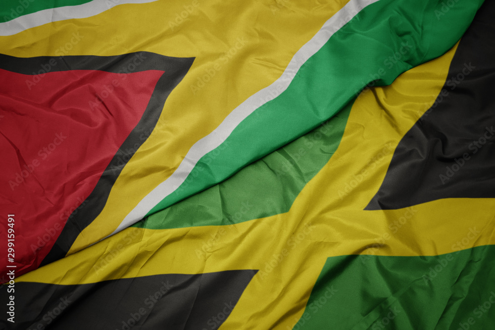 waving colorful flag of jamaica and national flag of guyana.