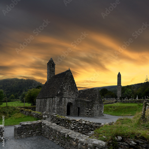 Canvas Print view to the ruins of monastic cemetery of Glendalough, Ireland while sunset , an