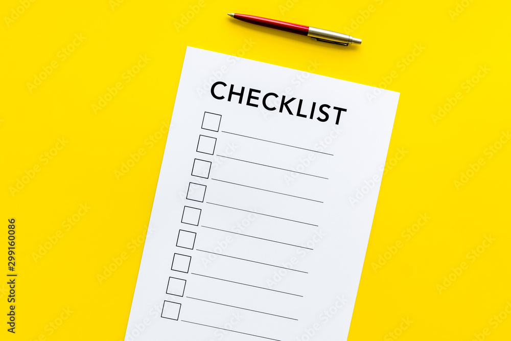 Checklist close up and pen on yellow background top view Checklist close up and pen on yellow background top view