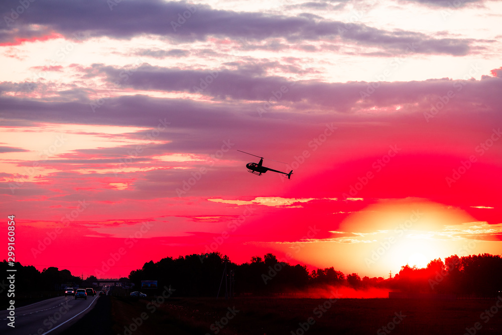 Silhouette of a chopper high in the evening sky at sundown seen from below, the line of the forest in contre-jour. Silhouette of a chopper high in the evening sky at sundown seen from below, the line of the forest in contre-jour.