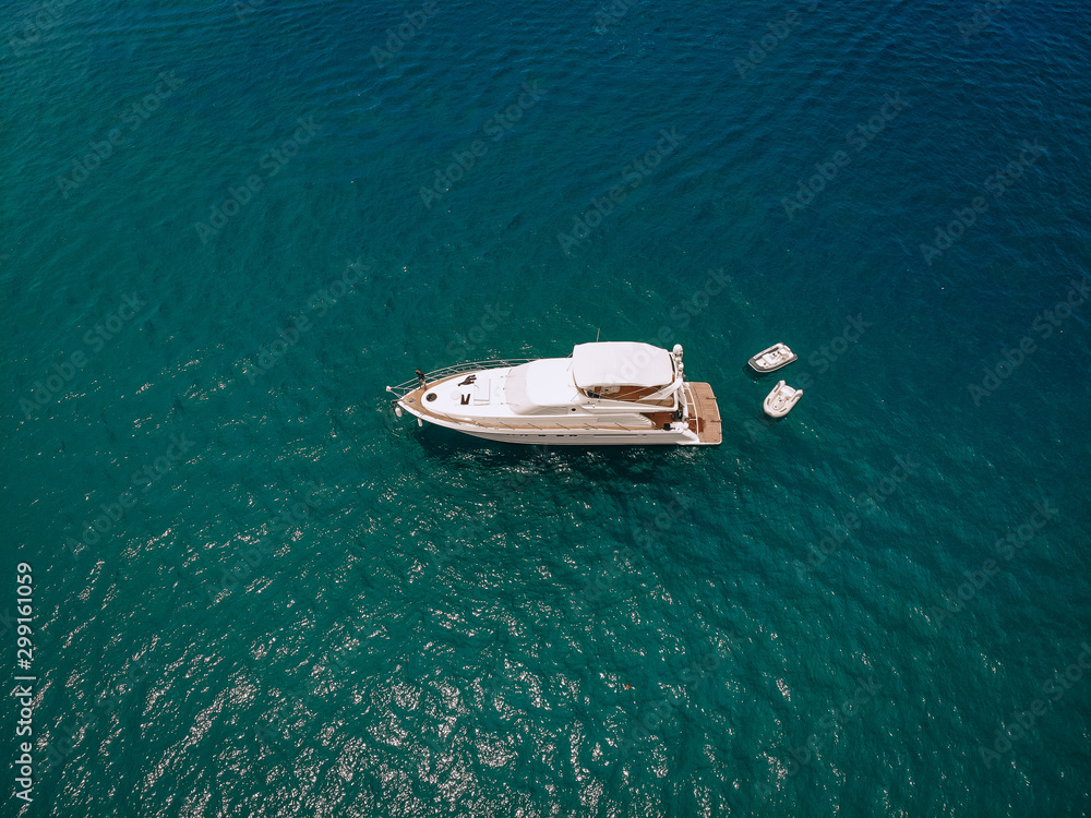 Drone shot of the beautiful white yacht in the warm blue sea; wealth concept. Drone shot of the beautiful white yacht in the warm blue sea; wealth concept.