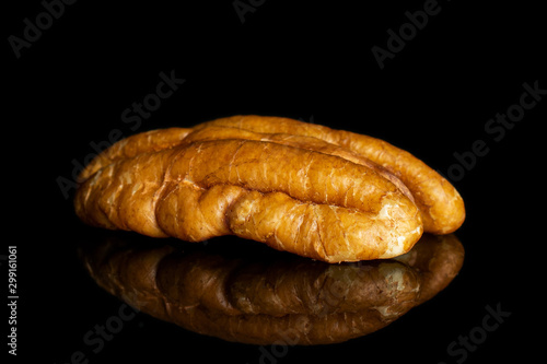 One whole dry brown pecan nut isolated on black glass