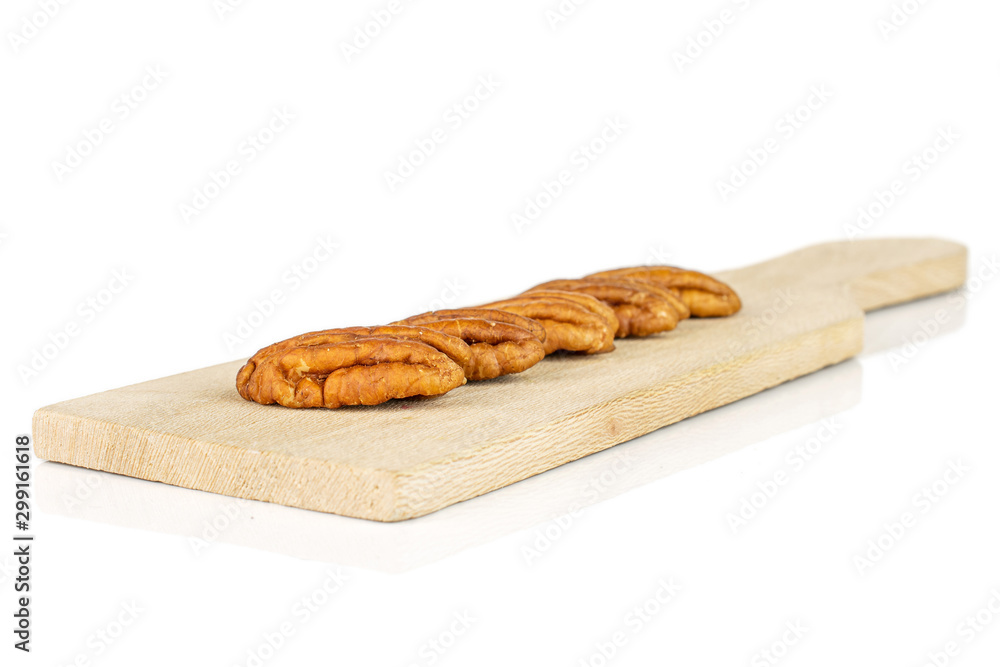 Group of five whole dry brown pecan nut on small wooden cutting board isolated on white background Group of five whole dry brown pecan nut on small wooden cutting board isolated on white background