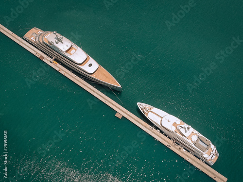 Top view of the luxurious white yachts moored at the long thin quay, blue sea in a sunny day; millionaire concept.