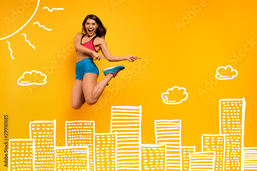 Sport woman jumps on a yellow background with Skyscrapers drawing. Happy and joyful expression.