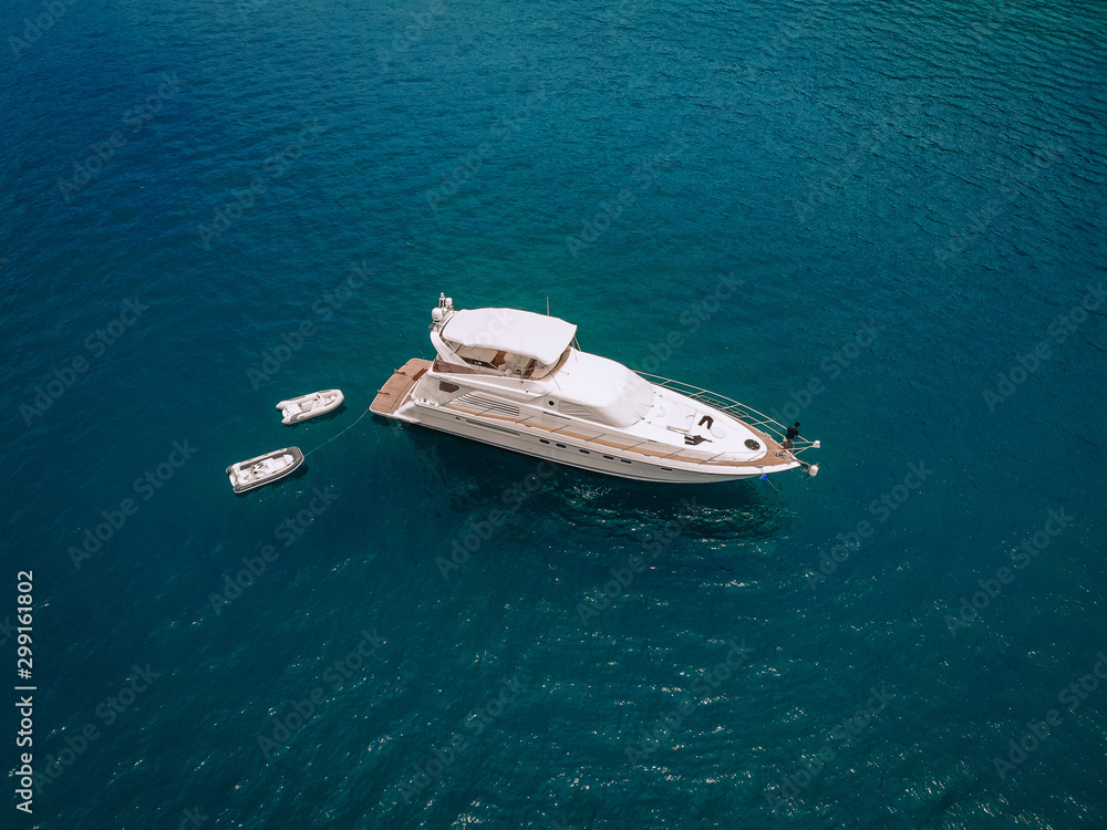 Drone shot of the beautiful white yacht in the warm blue sea; wealth concept. Drone shot of the beautiful white yacht in the warm blue sea; wealth concept.