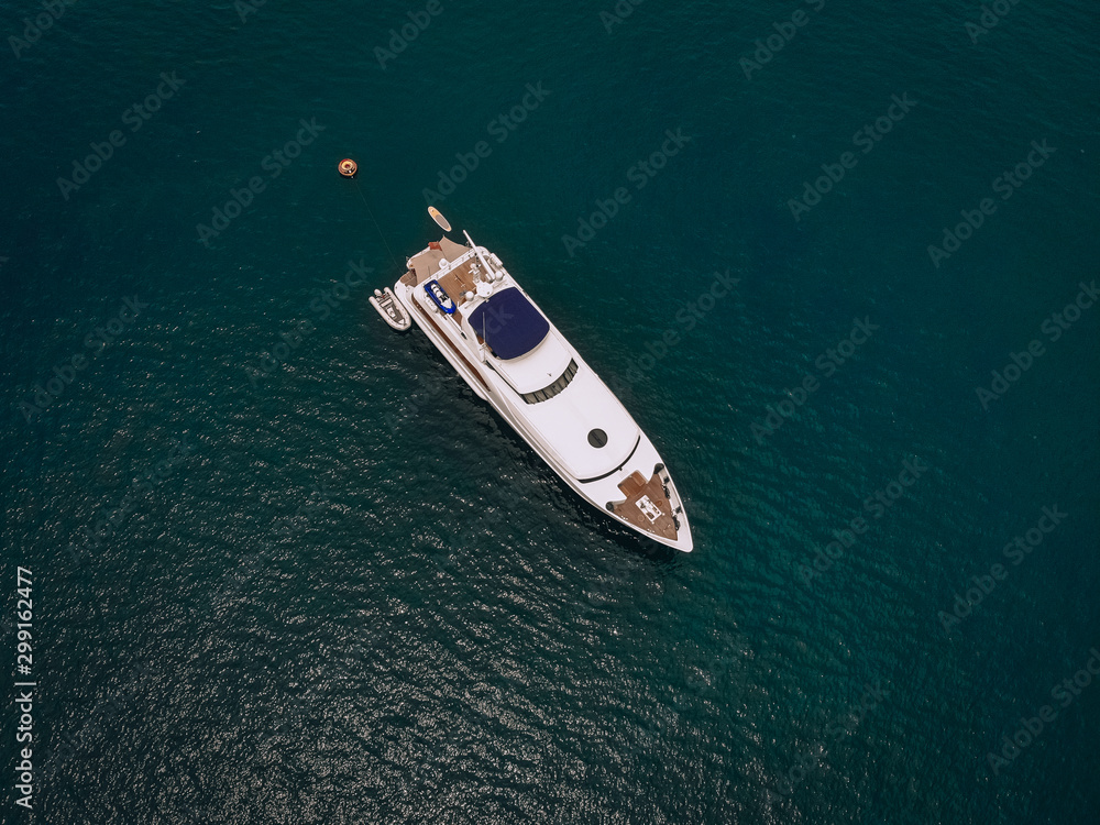 Drone shot of the beautiful white yacht in the warm blue sea; millionaire concept. Drone shot of the beautiful white yacht in the warm blue sea; millionaire concept.