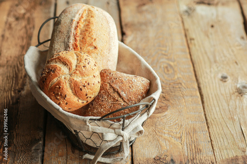 Bread in a basket on a black background. Assorted baking in a metal basket. Place for recipe and text. Background with rolling pin and flour. Rye bread and baguette with seeds. Buckwheat bread 