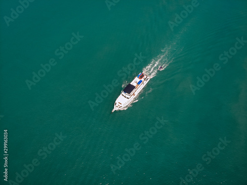 Aerial view of the speedboat and a boat behind it sailing near the coast of Thailand, white trace on the water; vessels concept.