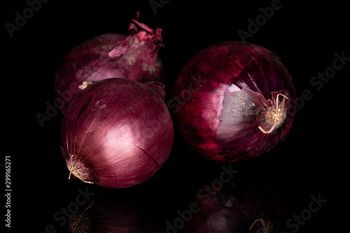 Group of three whole tasty onion red isolated on black glass
