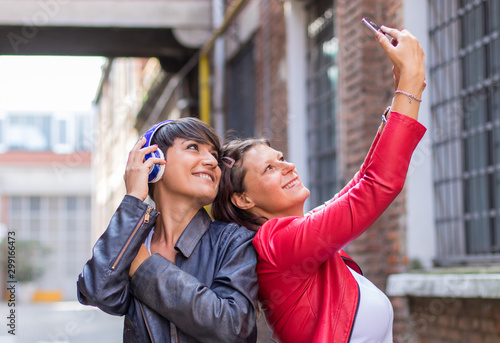 two friends are taking a selfie in a urban street