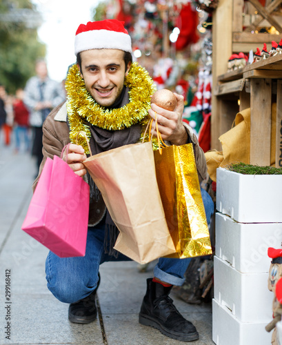 Young male in hat with purchases excited at Christmas market