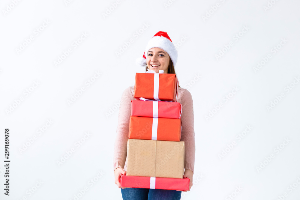 Holidays and people concept - Christmas santa woman shopping holding many gifts wearing santa hat smiling happy on white background with copy space
