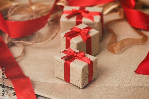 Set of gift boxes wrapped in craft paper and tie red satin ribbon. Christmas presents. Holiday mood. New year decor. Gift exchange. © exienator