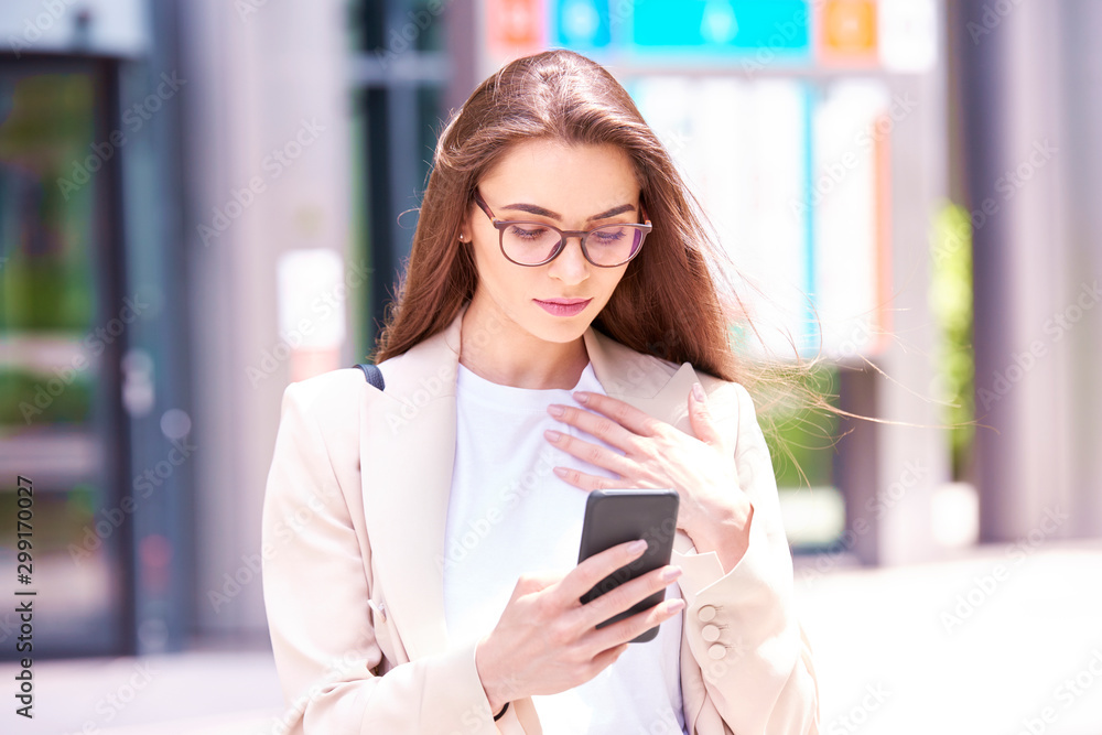 Fototapeta premium Young professional woman text messaging while standing on the street