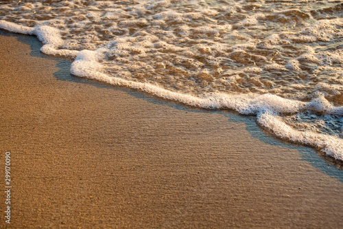 Small wave of the sea meets the sand on the shore of a sandy beach, oblique line