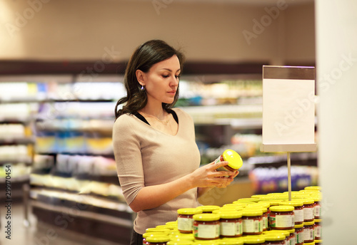 Woman who chooses products in the supermarket. Read product information.Concept of healthy food, bio, vegetarian, diet.