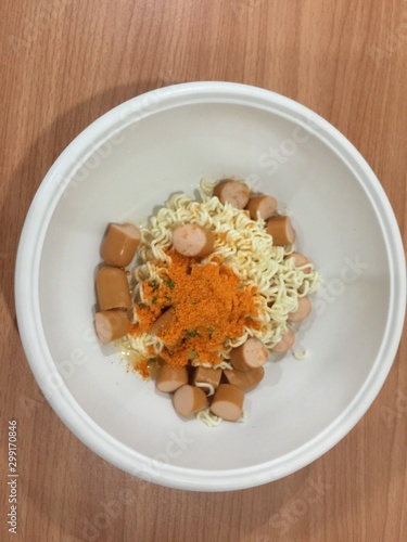 Pieces of noodles and hot dogs in a wooden floor cup