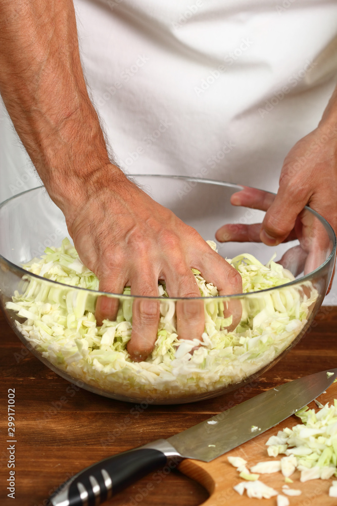 Cooking Cabbage. Pressing cabbage with salt in glass bowl.