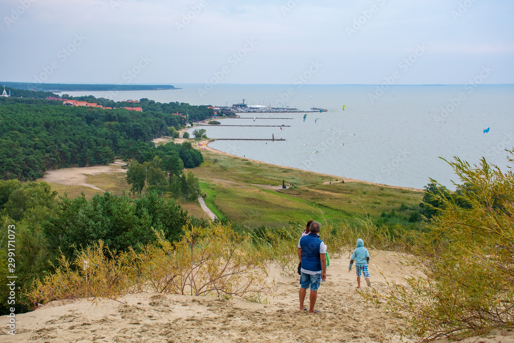 Panoramic view from sand dunes in Nida, Klaipeda, Lithuania, Europe. Curonian Spit and Curonian Lagoon, Nida harbour. Baltic Dunes. Unesco heritage. Tourists walking on the dunes
