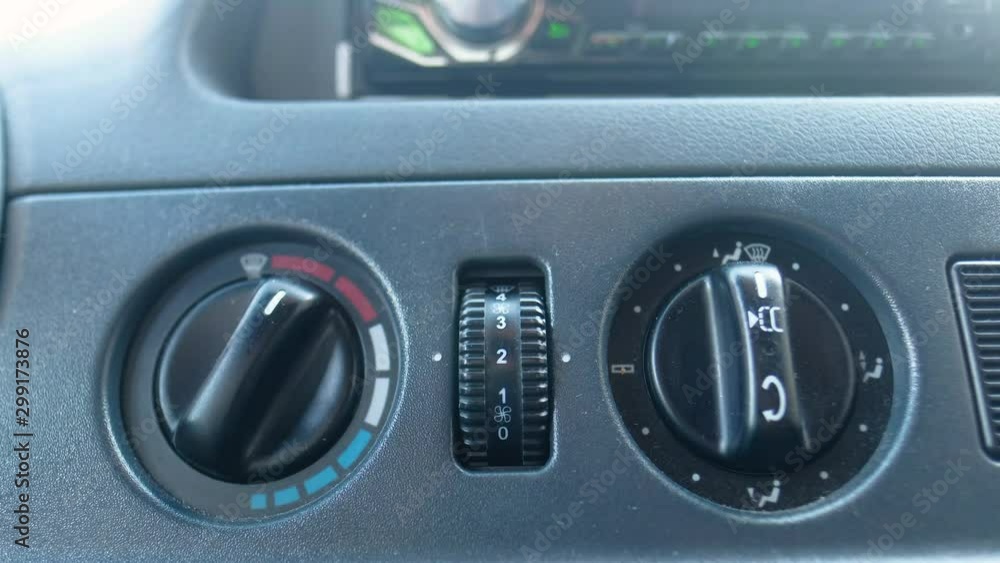Closeup of hand adjusting the air conditioner button in the car. Man using automobile air conditioning system. Dual climate control in the car. Closeup of hand adjusting the air conditioner button in the car. Man using automobile air conditioning system. Dual climate control in the car.