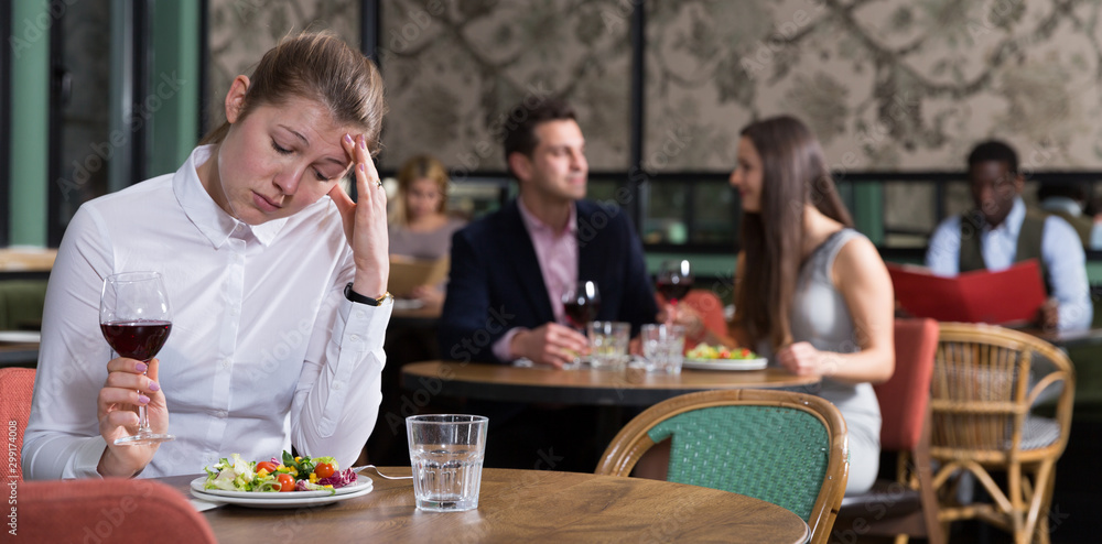 Unhappy young woman alone in restaurant