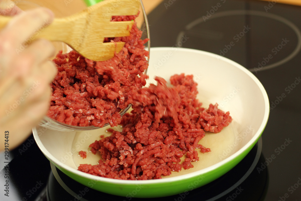 Adding ground beef into frying pan Adding ground beef into frying pan
