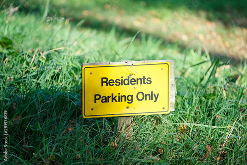 Residents parking only yellow sign on green grass