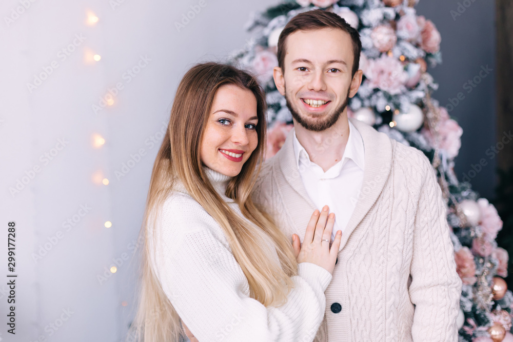 couple in love in white knitted sweaters on Christmas tree backg couple in love in white knitted sweaters on Christmas tree backg