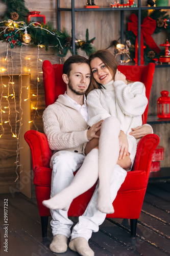 couple in love in white clothes sitting on red armchair on the b