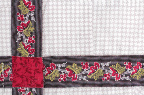 Fabric patchwork from colored fabrics with handmade folk ornament as a background, place for text.