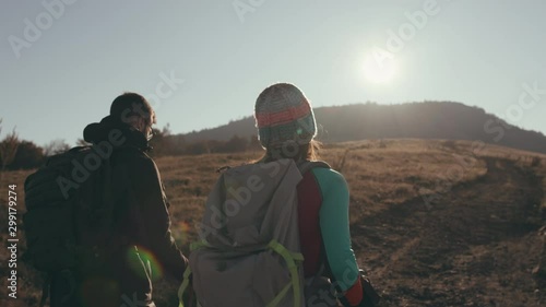 Back view of hikers climbing towards mountain top. Slow motion shot of man and woman hiking in the morning sun.
