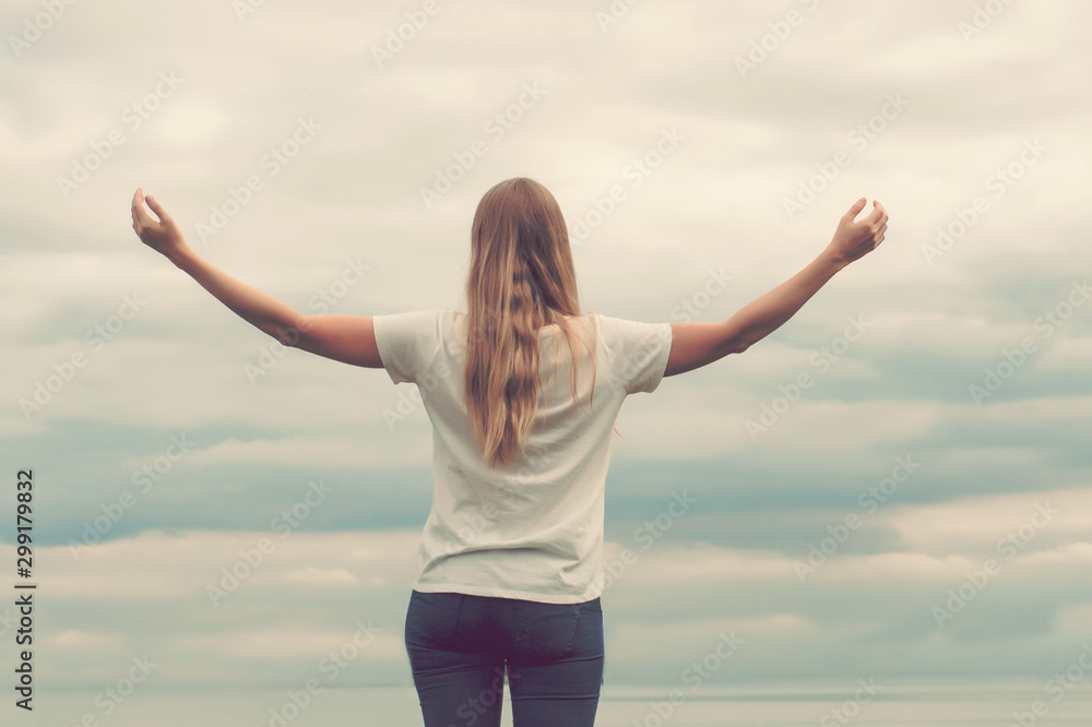 Beautiful girl on the lake. The view from the back. Hands up. Cloudy sky, sunset Beautiful girl on the lake. The view from the back. Hands up. Cloudy sky, sunset