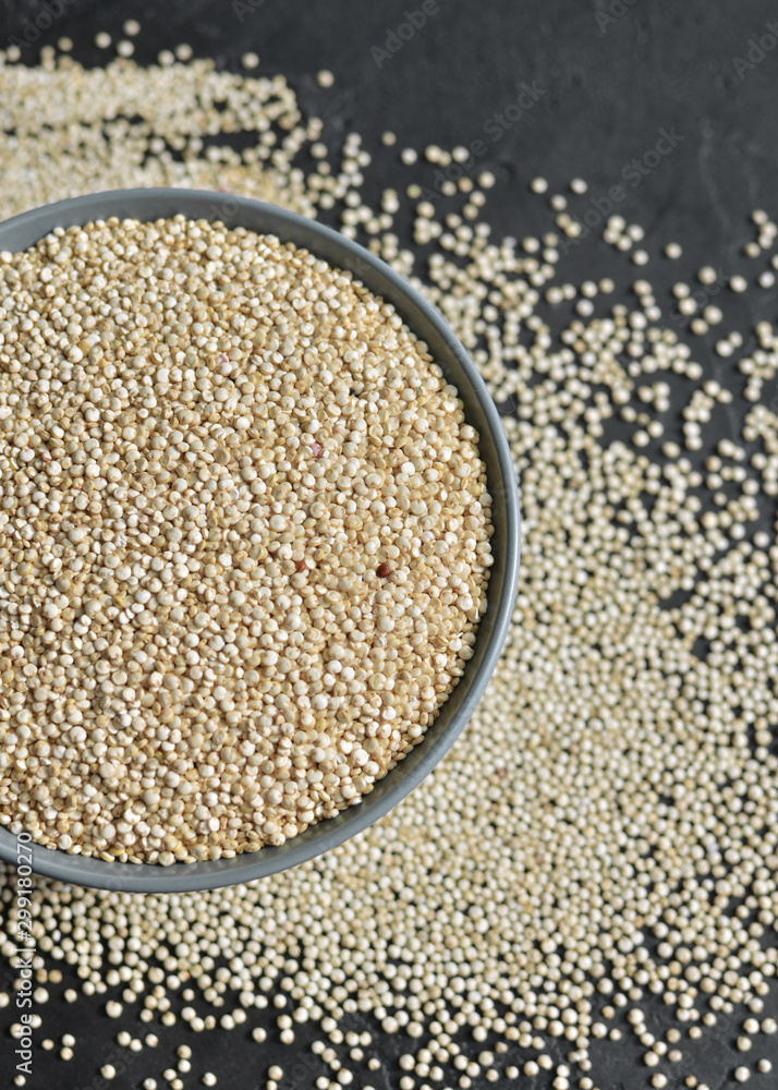 White dry quinoa seeds grain in ceramic plate over black stone background White dry quinoa seeds grain in ceramic plate over black stone background