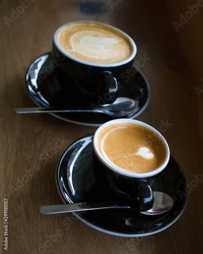 Espresso machiato with heart shaped latte art and a cup of cappuccino on a wooden counter photo