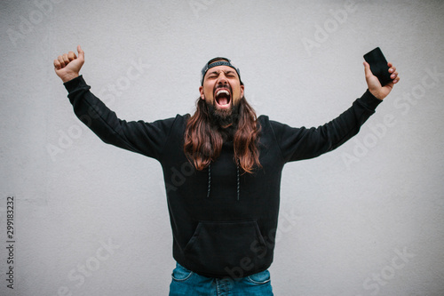 Happy hipster man celebrates victory after winning at an online bookmaker or casino. Crazy emotions. Jackpot photo