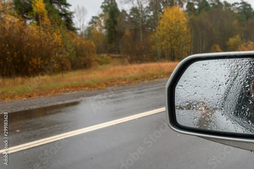Car rear view mirror in raindrops.Car headlights.
