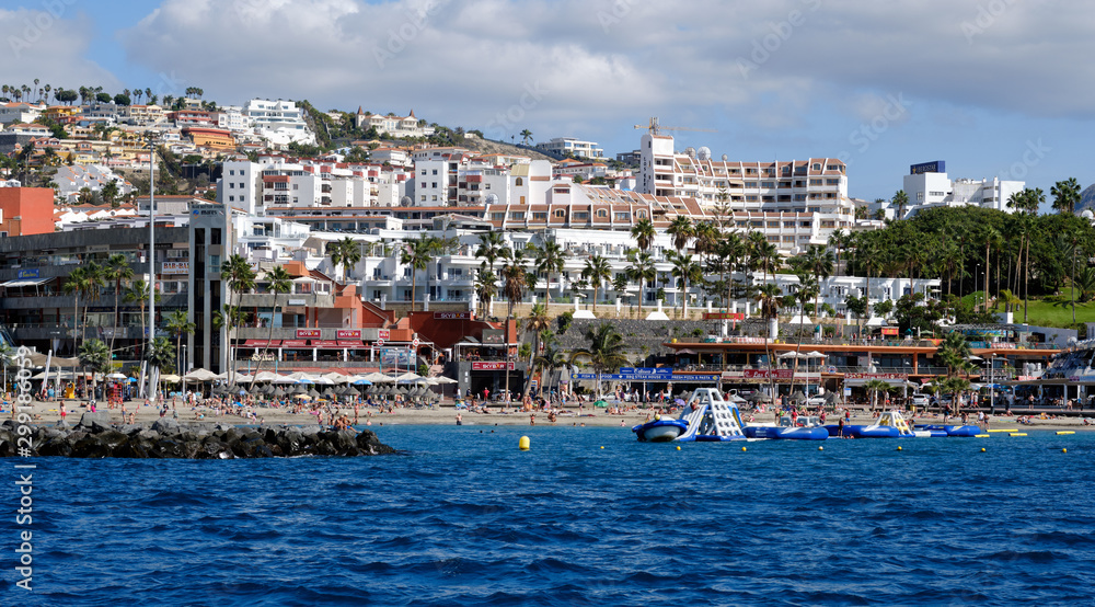 Waterside distant view Los Cristianos coastline, people enjoy warm Atlantic Ocean pretty beach, touristic town, situated on south coast of Canary Islands, Spain Waterside distant view Los Cristianos coastline, people enjoy warm Atlantic Ocean pretty beach, touristic town, situated on south coast of Canary Islands, Spain