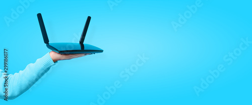 black wifi router on hand over blue background, panoramic mock up image photo