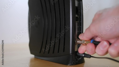 Connecting coaxial cable to cable modem. Man installing high speed broadband internet access.