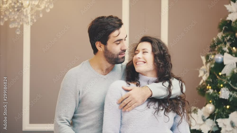 Romantic couple dancing and appreciating time together at home with Christmas Tree on gray background. Romantic couple dancing and appreciating time together at home with Christmas Tree on gray background.