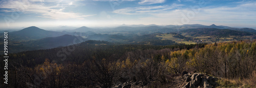 panoramic view from Hochwald Hvozd one of the most attractive view-points of the Lusatian Mountains with autumn colored deciduous and coniferous tree forest and green hills, golden hour light