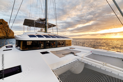 Fotografia, Obraz Solar powered catamaran at sunset, fully sustainable and powered by solar energy, charging batteries aboard a sailboat, vessel in ocean waters, nobody