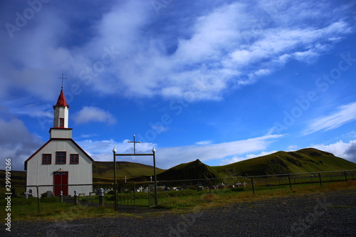 Iglesia blaca y roja en prado verde y cielo azul en Islandia