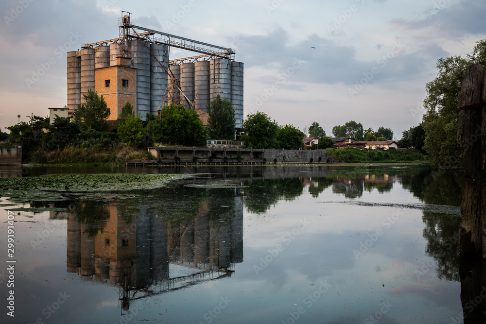 Old factory with silos and reflection on the water landscape