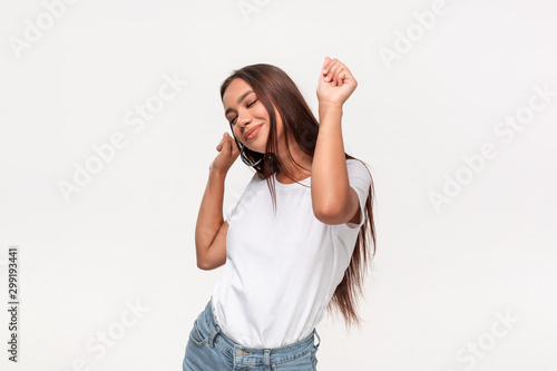 Beautiful african-american teenager in a white t-shirt and blue jeans dancing isolated over white background.