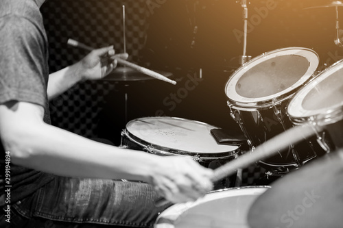 Young musicians wear t-shirts, jeans, and play the drum set and cymbals with wooden drumsticks in music room , the concept of musical instrument.