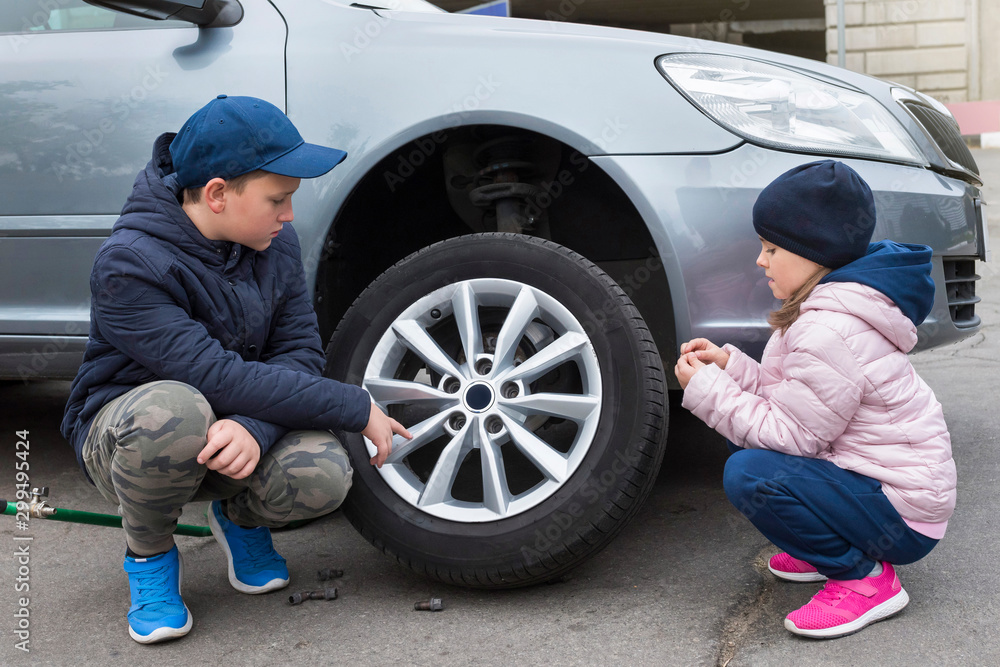 Boy and girl at a car service. Wheel replacement on a car, repair services.